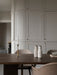 A dark oak Androgyne Dining Table featuring a Duca Candle Holder and Bottle Grinders, with beige Harbour Chairs.