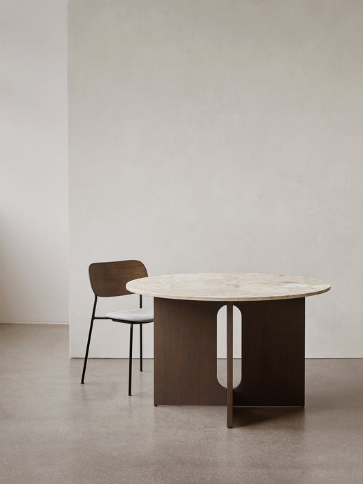 The round Androgyne Dining Table with a marble top, shown with the dark oak Co Dining Chair in a minimalist interior.