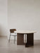 The round Androgyne Dining Table with a marble top, shown with the dark oak Co Dining Chair in a minimalist interior.