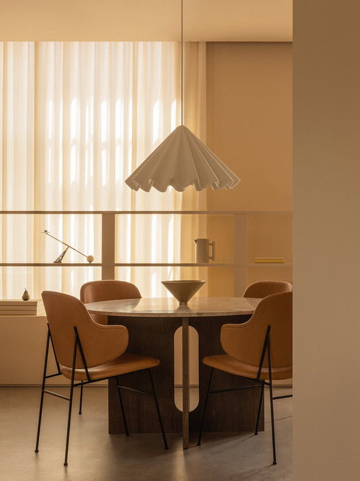A round Androgyne Dining Table with tan Penguin Dining Chairs and a Taper Bowl, lit by a white Dancing Pendant overhead.