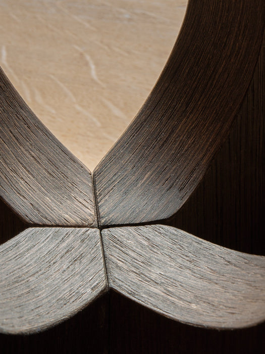 A close-up, top-down view of the Androgyne Dining Table's base, showing the intricate joinery of four dark oak panels.