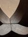 A close-up, top-down view of the Androgyne Dining Table's base, showing the intricate joinery of four dark oak panels.