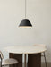 A black Levitate Pendant hangs over the round Androgyne Dining Table with a marble top, flanked by two upholstered Co Chairs.