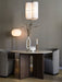 Round Androgyne Dining Table with stone top and dark oak base, set for two with grey chairs in a warm, ambiently lit room.