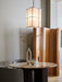 A round Androgyne Dining Table with a marble top and dark base, styled with vases and a candle, under a lit Hashira lamp.