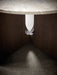 A detailed close-up of the Androgyne Dining Table's base, showing the dark oak wood and unique cut-out on a terrazzo floor.