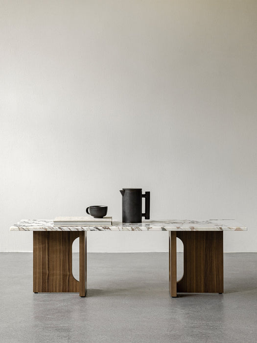 Front view of the Androgyne Lounge Table with a walnut wood base and Calacatta Viola marble top, styled with a black pitcher.