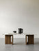 Front view of the Androgyne Lounge Table with a walnut wood base and Calacatta Viola marble top, styled with a black pitcher.