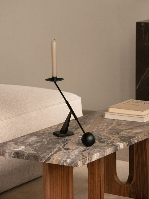 A black Interconnect Candle Holder on an Androgyne Lounge Table with a Grey Galaxy marble top and dark wood base.