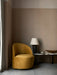 A Tearoom Lounge Chair in yellow velvet beside a marble Androgyne Lounge Table, styled with a black Torso Table Lamp.