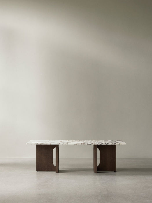 Androgyne Lounge Table with a white marble top and dark stained oak base, viewed front-on in a minimalist room.