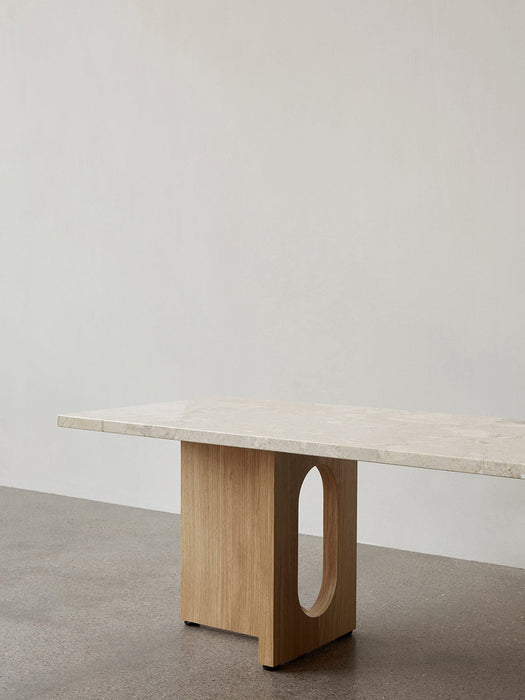 Side view of the Androgyne Lounge Table with a Kunis Breccia stone top and a natural oak base featuring an oval cutout.