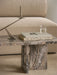 A close-up of the Androgyne Lounge Table in Grey Galaxy marble, styled with books and a candle holder next to a cream sofa.