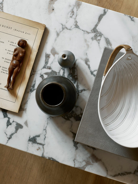A top-down detail shot of the marble Androgyne Lounge Table, styled with decorative vases, a book, and a wooden figurine.