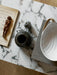 A top-down detail shot of the marble Androgyne Lounge Table, styled with decorative vases, a book, and a wooden figurine.