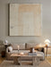 The Androgyne Lounge Table in stone, styled in a living room with a beige sofa, textured rug, and large abstract artwork.