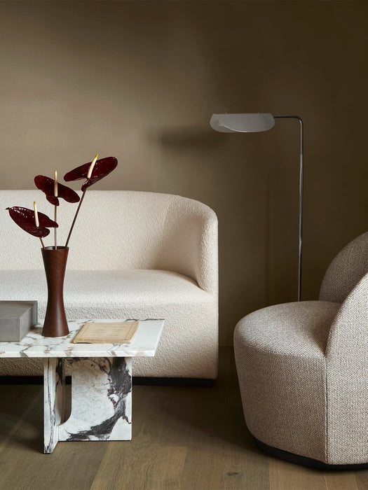 The Androgyne Lounge Table next to a Tearoom Sofa, Lounge Chair, and Wing Floor Lamp in a softly lit living room setting.