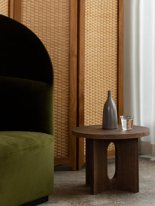 A dark oak Androgyne Side Table with a Strandgade Stem Vase and glass, next to a green velvet Tearoom Lounge Chair.