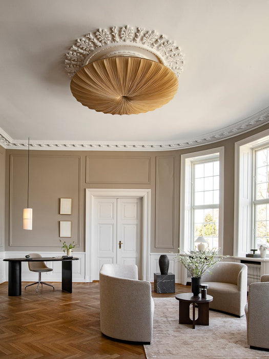 A spacious, classic room with beige walls, herringbone floors, and an Androgyne Side Table amidst several plush armchairs.