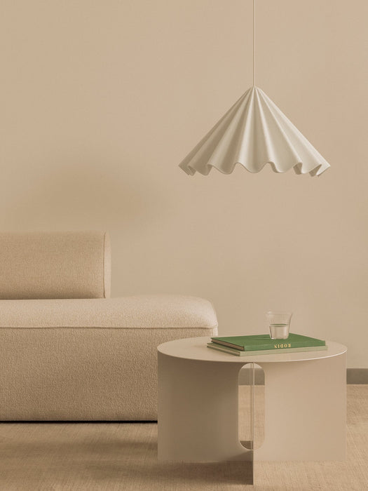 A beige living room with a textured Eave Modular Sofa, an ivory Androgyne Side Table, and a white, pleated Dancing Pendant.