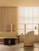 A warm-toned living room featuring a beige Brasilia Sofa, a black Androgyne Side Table, and a curved Tearoom Side Chair.