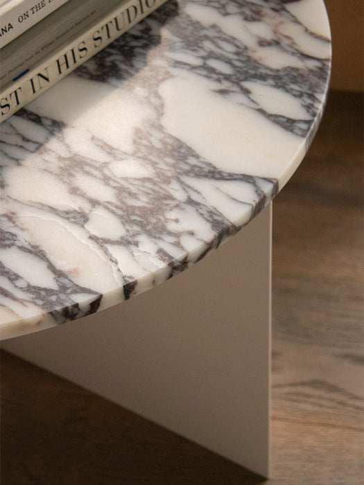 A close-up of the Androgyne Side Table, showing the detailed veining of the Grey Galaxy marble top with books on it.