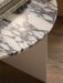 A close-up of the Androgyne Side Table, showing the detailed veining of the Grey Galaxy marble top with books on it.