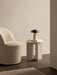 A cream Tearoom Club Chair Swivel beside an Androgyne Side Table with a book, glass and Reverse Table Lamp Portable.