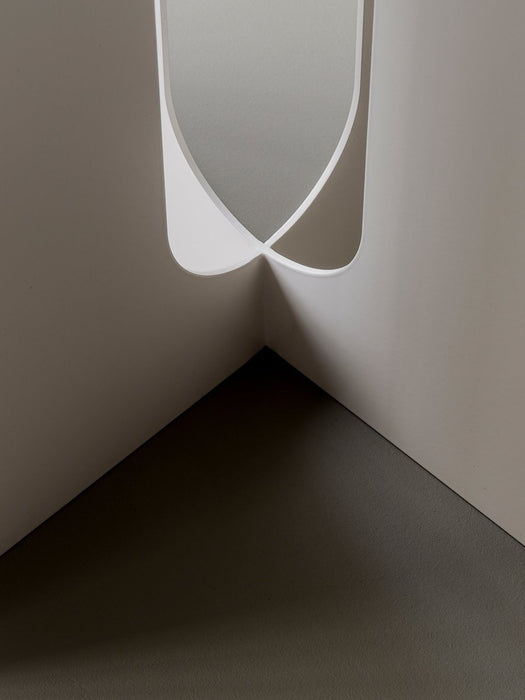 A close-up, high-angle shot of the ivory steel base of the Androgyne Side Table, showing the curves where the legs meet.