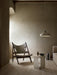 The Androgyne Side Table styled in a minimalist room next to the wooden Knitting Chair, with a Hubert Pendant hanging above.