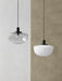 Two Bank Pendant lights, one with a smoked glass shade and one with an opal glass shade, hang against a split-tone wall.