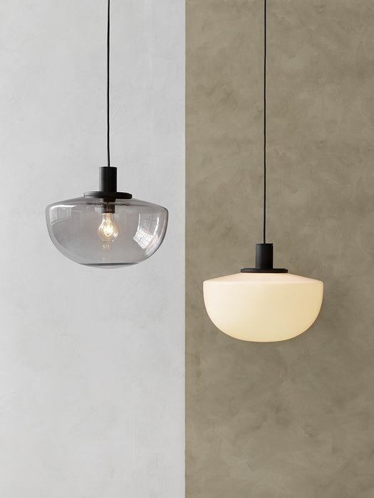 Two Bank Pendants, one in smoked glass and one in opal glass, hanging side-by-side against a two-toned textured wall.