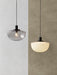 Two Bank Pendants, one in smoked glass and one in opal glass, hanging side-by-side against a two-toned textured wall.