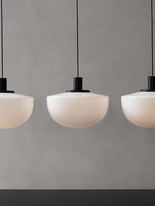 Three Bank Pendant lights with opal glass shades and black fittings, hanging in a row against a textured grey wall.