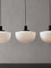 Three Bank Pendant lights with opal glass shades and black fittings, hanging in a row against a textured grey wall.