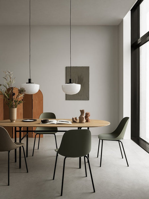 Two white Bank Pendants hanging over a wooden Snaregade Table with green Harbour Dining Chairs in a modern dining room.