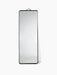 The Norm Floor Mirror in black, a full-length rectangular mirror with rounded corners, a thin frame and a leather strap.