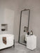 The Norm Floor Mirror leans next to a marble Plinth in a minimalist bathroom with a white freestanding tub.