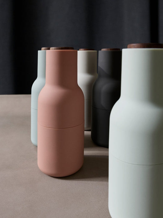 A collection of Audo's Bottle Grinders, designed by Norm Architects, in matte colours including pink, green, and charcoal.