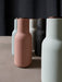 A collection of Audo's Bottle Grinders, designed by Norm Architects, in matte colours including pink, green, and charcoal.