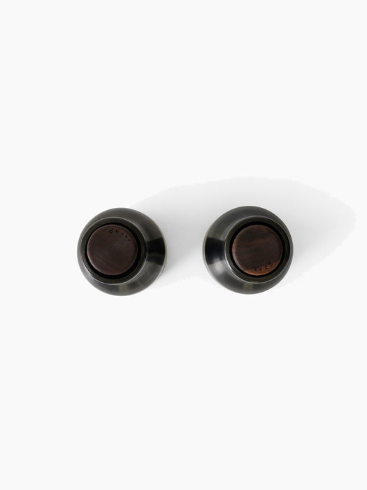 Top-down view of two Bottle Grinders. They have bronzed brass bodies and dark walnut lids, shot on a white background.