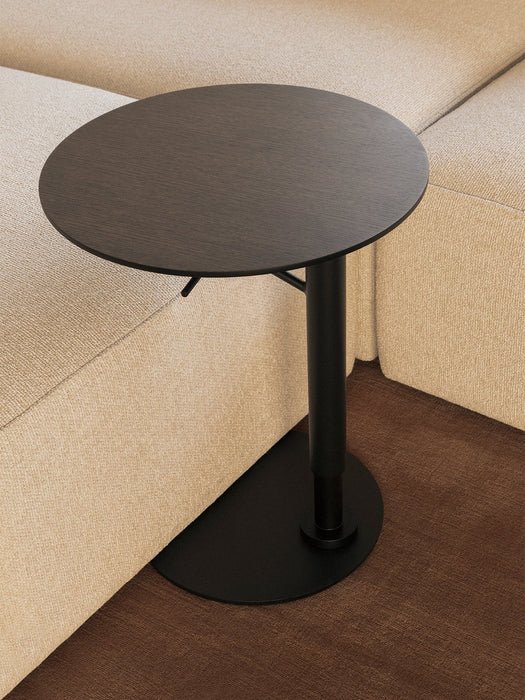 A high-angle, close-up view of the Branch Side Table in dark stained oak, its black base tucked next to a beige Eave sofa.