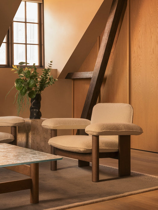 The Brasilia Lounge Chair, Low Back, in light upholstery, styled with a Brasilia table and Duomo Rug in a warm, wooden room.