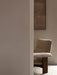 Partial view of the Brasilia Lounge Chair in beige textile with dark wood frame, sitting on a textured Houkime Rug.