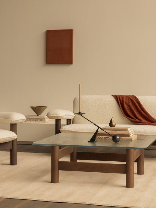 A Brasilia Lounge Table with a glass top. On the table is an Interconnect Candle Holder in front of a cream Brasilia Sofa.