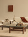 A Brasilia Lounge Table with a glass top. On the table is an Interconnect Candle Holder in front of a cream Brasilia Sofa.