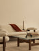 Cream Brasilia Sofa with a rust throw. In front, a glass Brasilia Lounge Table with an Interconnect Candle Holder and books.