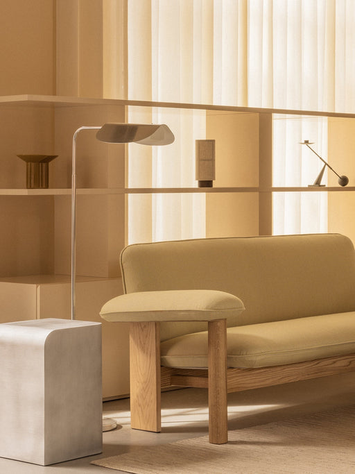 A detailed shot of the Brasilia Sofa next to the Volume Side Table and Wing Floor Lamp in a room with warm, natural light.