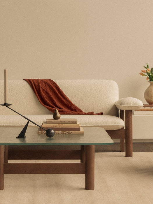 Close-up of Brasilia Lounge Table with Interconnect Candle Holder and books. In the background, a Brasilia Sofa in sheepskin.