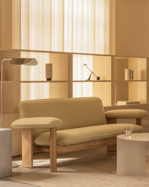 The Brasilia Sofa, with a natural oak frame and light-coloured upholstery, styled in a warm, beige-toned living room setting.